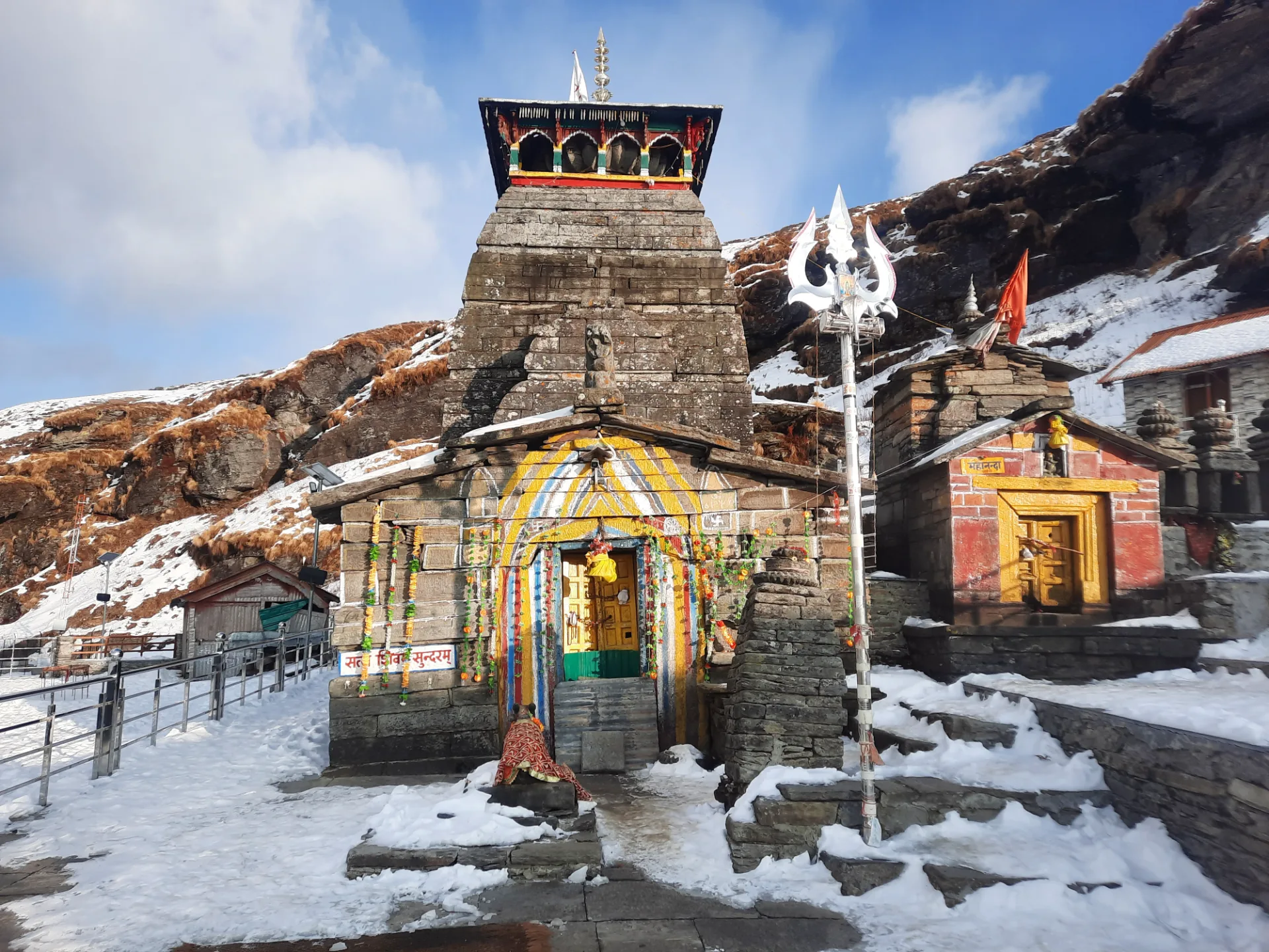 Stone Tungnath Temple and its entrance with snow on the ground.