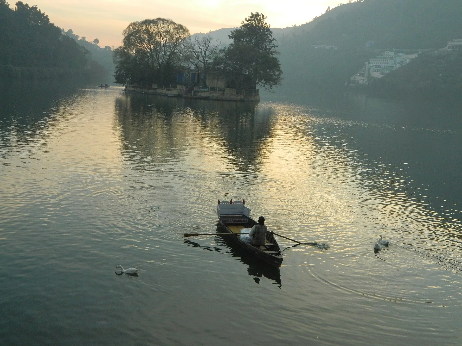 Rowboat crossing misty Bhimtal Lake at dusk